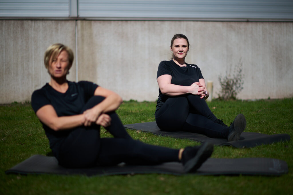 Två personer som sitter och stretchar på marken.